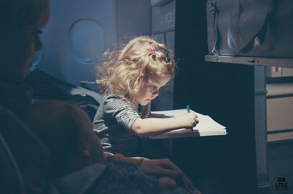 Dziecko w samolocie rysuje w książeczce