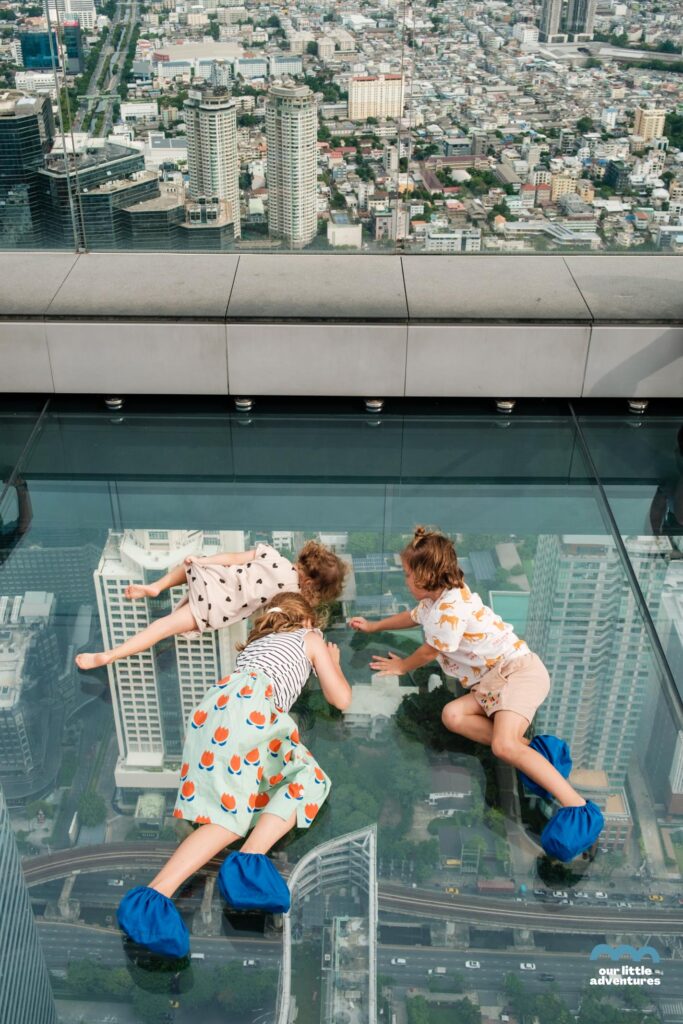 Dzieci leżą na tarasie widokowym Sky Walk w Bangkoku, King Power Mahanakh, najwyższy budynek Tajlandii, fot. OurLittleAdventures.pl