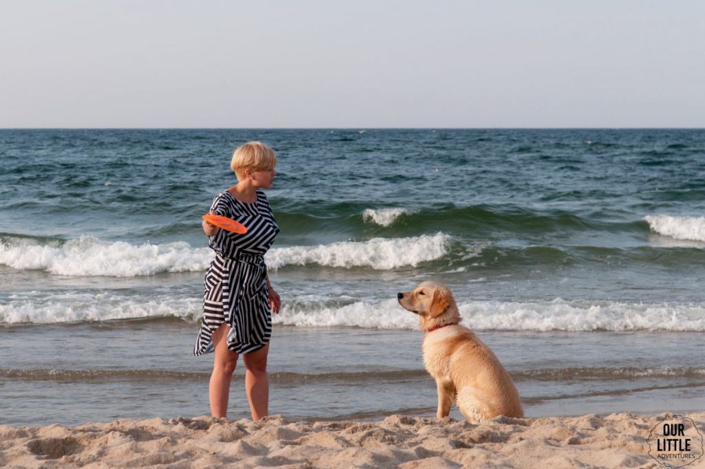 Kobieta i pies na plaży we Władysławowie. Kobieta ma zamiar rzucić frisbee 