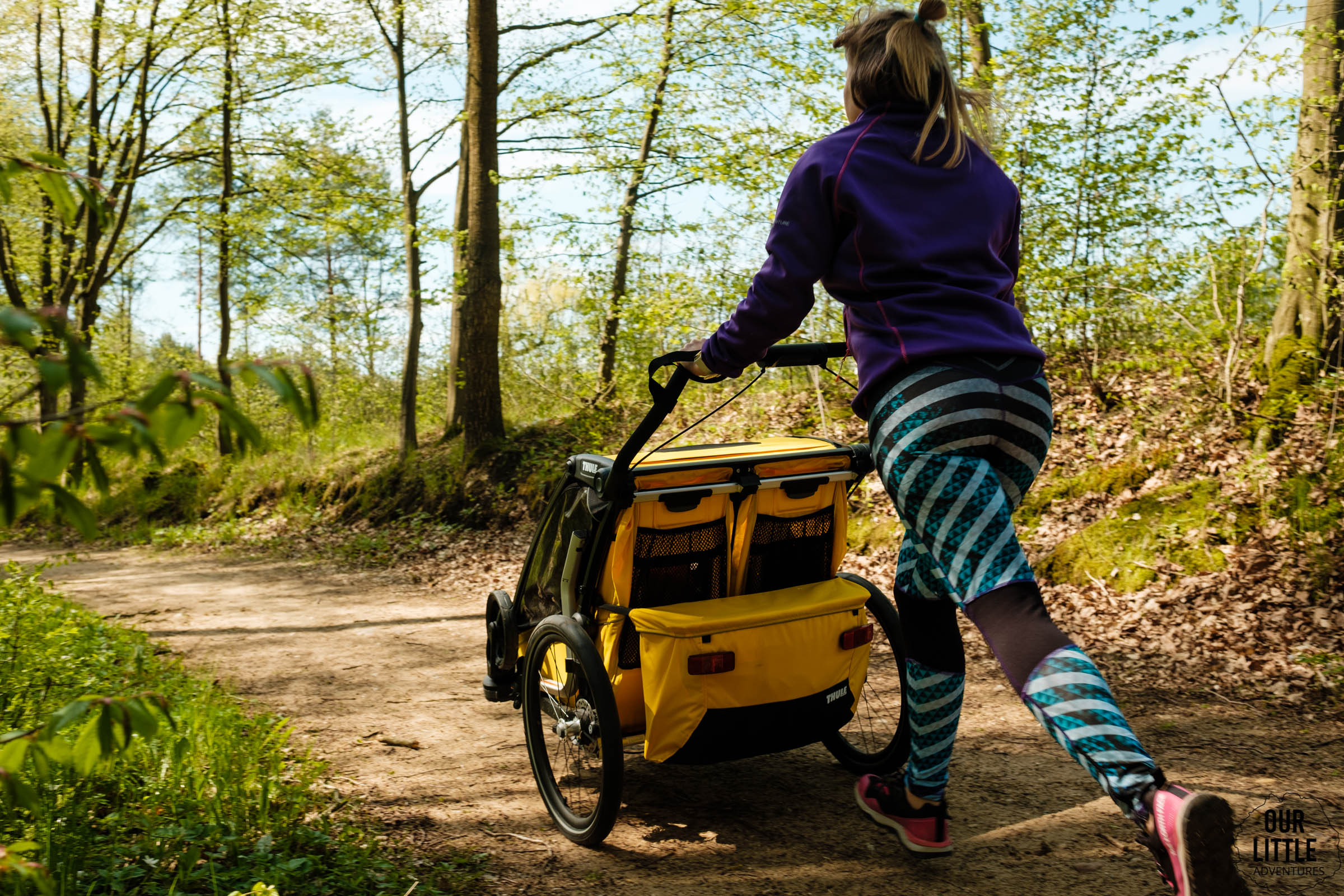 Kobieta w lesie biega z przyczepką do biegania Thule sport 2