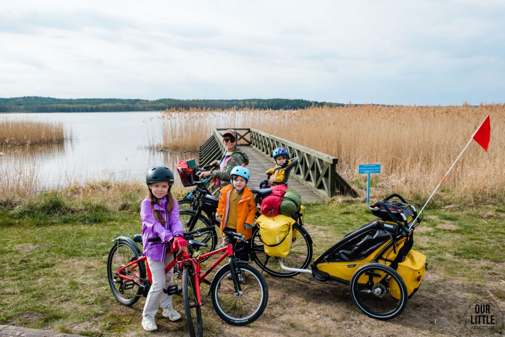 Jezioro Charzykowskie, rodzina na rowerach stoi przy pomoście, Bory Tucholskie - Kaszubska Marszruta z dziećmi, zdjęcie autorstwa OurLittleAdventures.pl