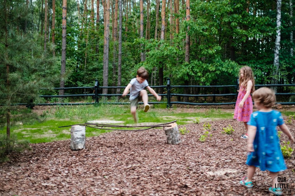 Dzieci bawią się obok domku, skacząc przez przeszkody, Bezpieczne wakacje z dziećmi, zdjęcie autorstwa OurLittleAdventures.pl