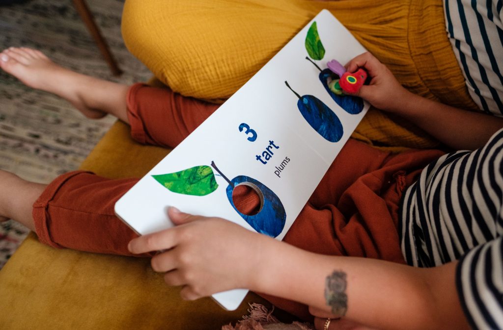 Chłopiec siedzi na kanapie z książką, ilustracja tekstu Angielski dla dzieci, fot. OurLittleAdventures.pl