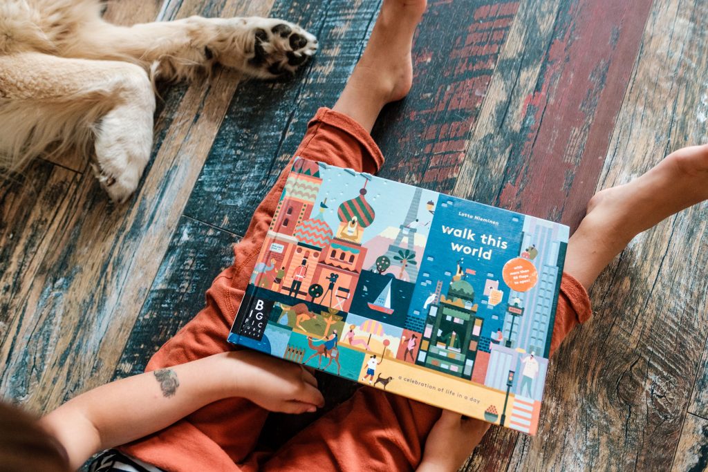 Chłopiec siedzi na podłodze z książką, ilustracja tekstu Angielski dla dzieci, fot. OurLittleAdventures.pl