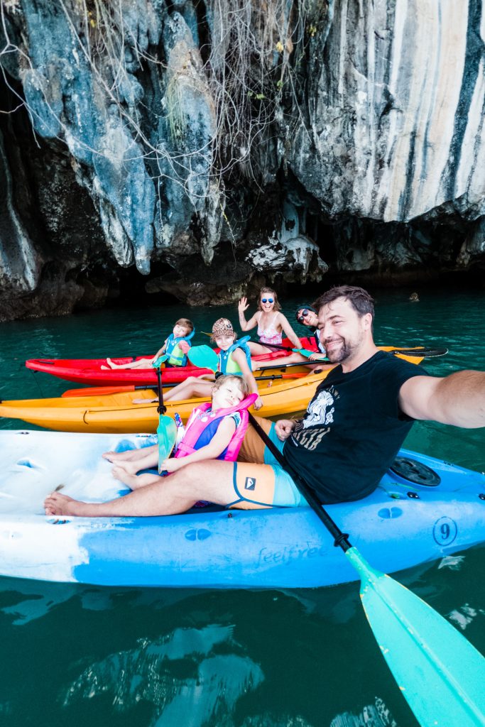 Koh Lanta - 5 powodów, aby spędzić wakacje na Koh Lancie - subiektywny przewodnik po wyspie, zdjęcie OurLittleAdventures.pl, na którym rodzina siediz w kajakach na tle skały przy Koh Talabeng