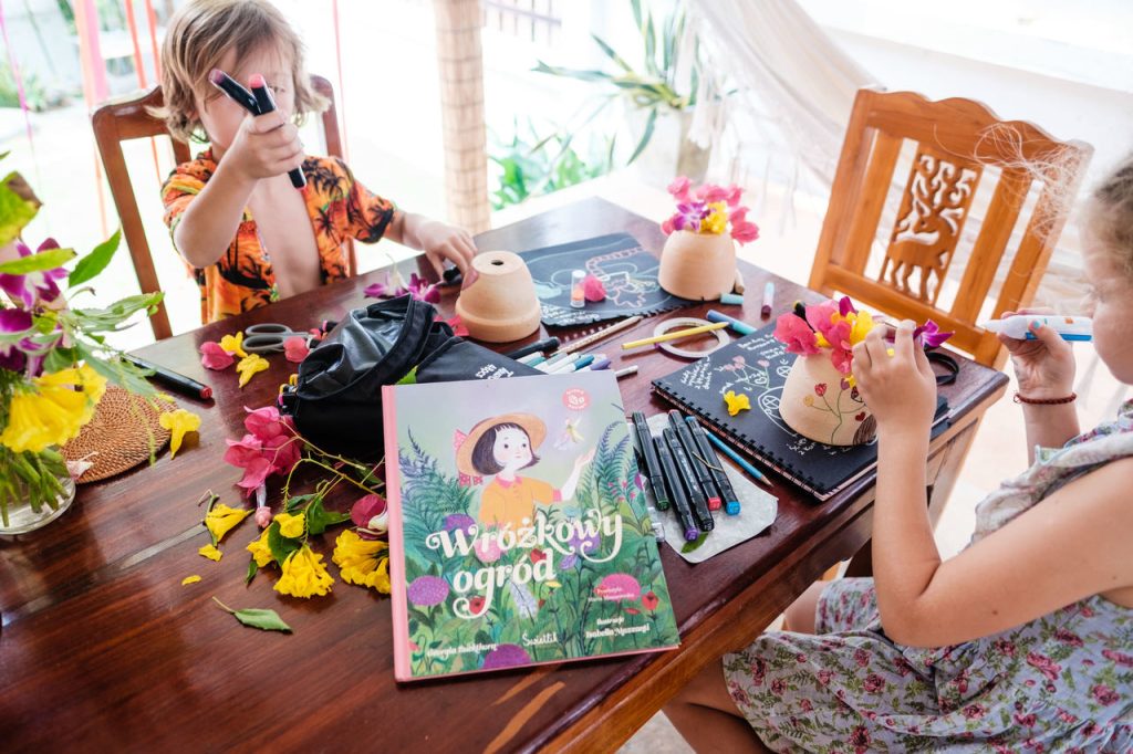 Książka "Wróżkowy ogród" wydawnictwo Świetlik leży na stole, dzieci wykonują prace plastyczne, zdjęcie pochodzi ze strony OurLittleAdventures.pl - książki przyrodnicze dla dzieci