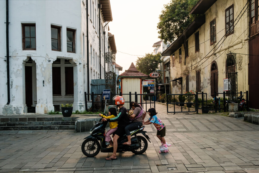 5-osobowa rodzina jedzie na skuterze, dziewczynka trzyma się skutera i jedzie na rolkach - zdjęcie pochodzi z bloga OurLittleAdventures.pl z tekstu Jakarta - co zobaczyć w stolicy Indonezji?