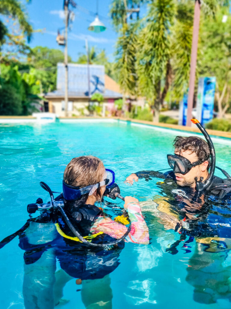 Mężczyzna i dziecko  w strojach nurków w basenie - zdjęcie pochodzi z bloga OurLittleAdventures.pl z tekstu: Jak zacząć nurkować? - wszystko, co musisz wiedzieć o nurkowaniu