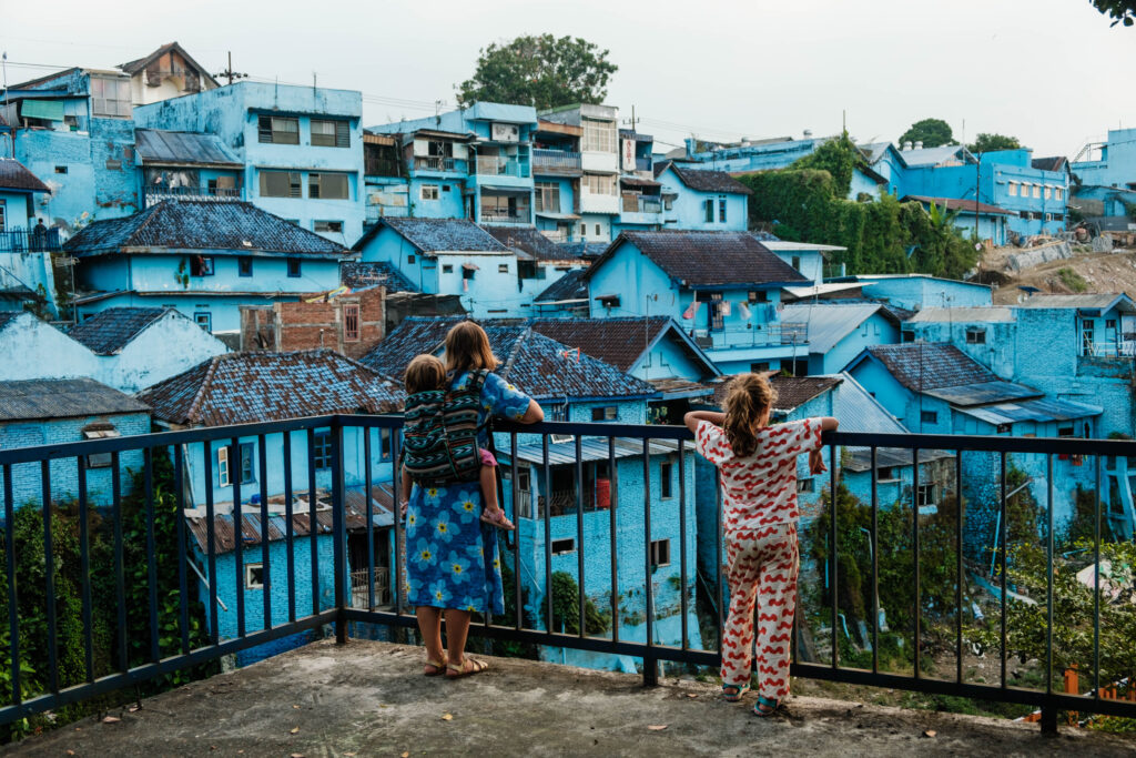 Kobieta z dwojgiem dzieci patrzy na Niebieską Dzielnicę Jodipan w Malangu, zdjęcie pochodzi z tekstu Jodipan - niezwykła kolorowa dzielnica Malangu, blog OurLittleAdventures.pl