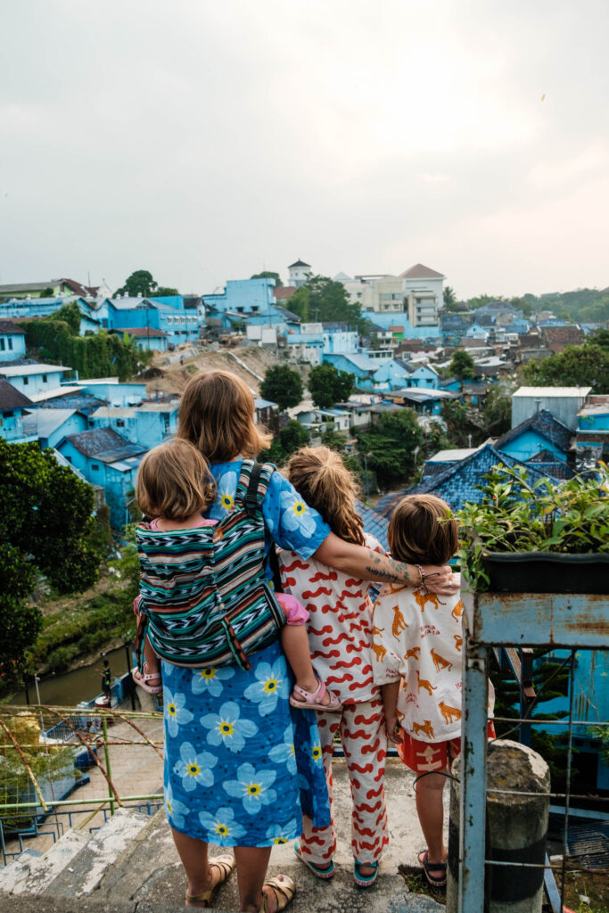 Kobieta z dwojgiem dzieci patrzy na Niebieską Dzielnicę Jodipan w Malangu, zdjęcie pochodzi z tekstu Jodipan - niezwykła kolorowa dzielnica Malangu, blog OurLittleAdventures.pl