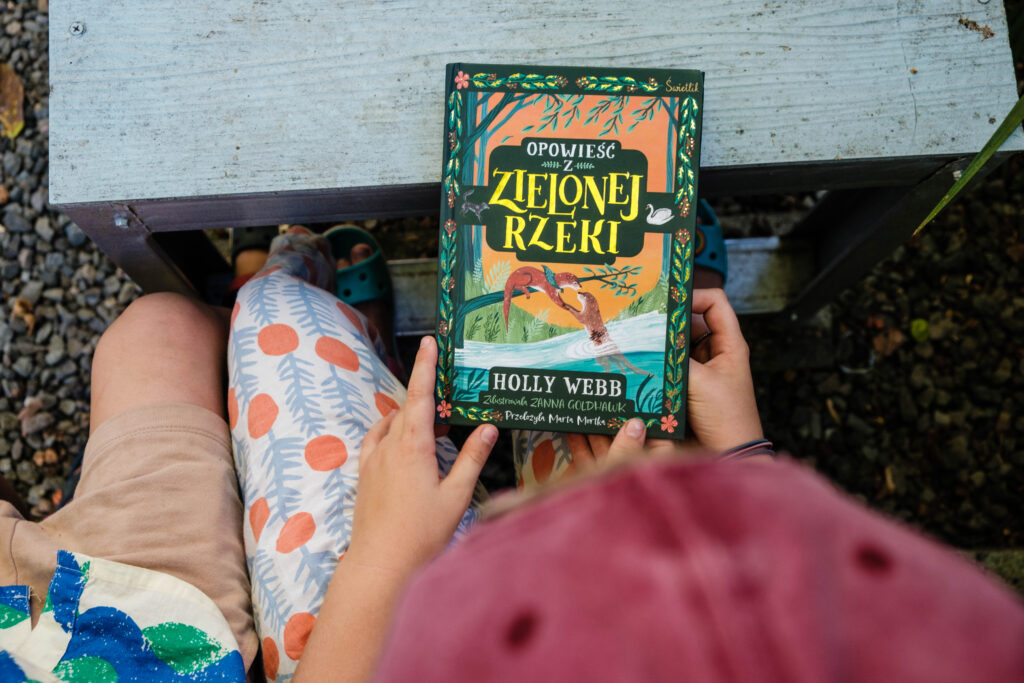 Dzieci trzymają książkę Opowieść z Zielonej Rzeki, Holly Webb, wydawnictwo Świetlik, fot. OurLittleAdventures.pl
