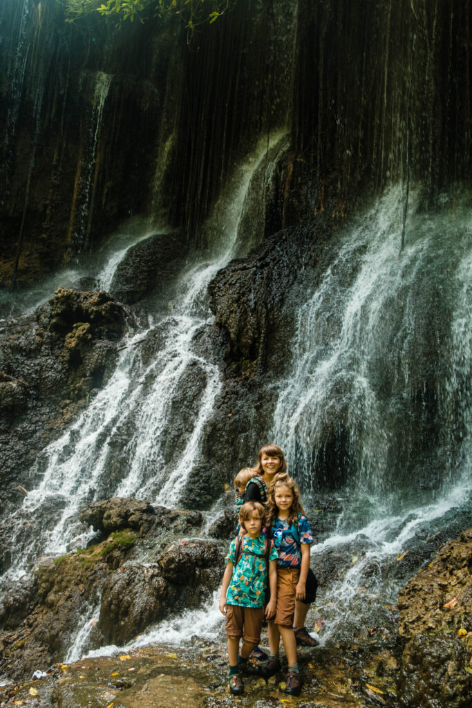 Rodzina stoi w rozpryskującej się wodzie wodospadu Tumpak Sewu na Jawie - zdjęcie autorstwa OurLittleAdventures.pl pochodzi z tekstu: Tumpak Sewu - najpiękniejszy wodospad w Indonezji