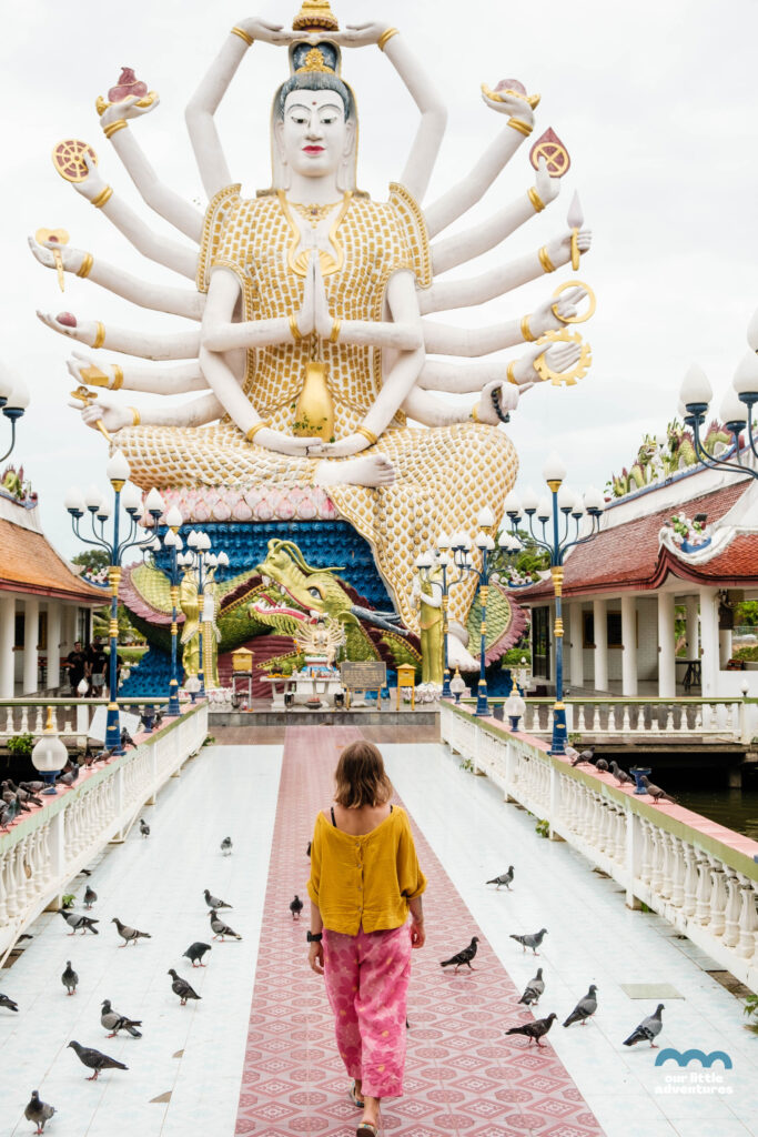 Kobieta na tle posągu Buddy w świątyni Wat Plai Laem na wyspie Koh Samui; zdjęcie pochodzi z tekstu Koh Samui co warto zobaczyć - 5 miejsc, tekst z bloga Ourlittleadventures.pl