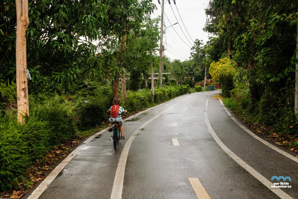 Dziecko jadące na rowerze po ulicy w Bang Kraczao w Bangkoku - zdjęcie pochodzi z tekstu na blogu OurLittleAdventures.pl pt. Wyspa Bang Krachao - wycieczka rowerowa z dziećmi do zielonej oazy Bangkoku