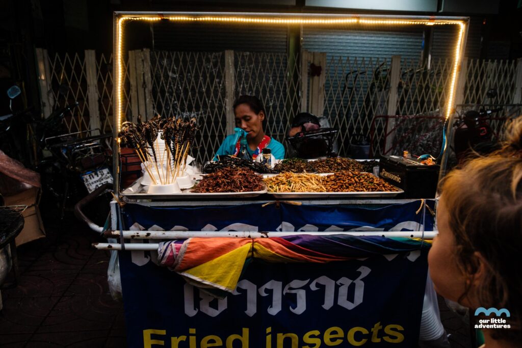 Widok na zatłoczoną ulicę i stoisko z szarańczą i skorpionami w Chinatwon w Bangkoku, zdjęcie z bloga  OurLittleAdventures.pl