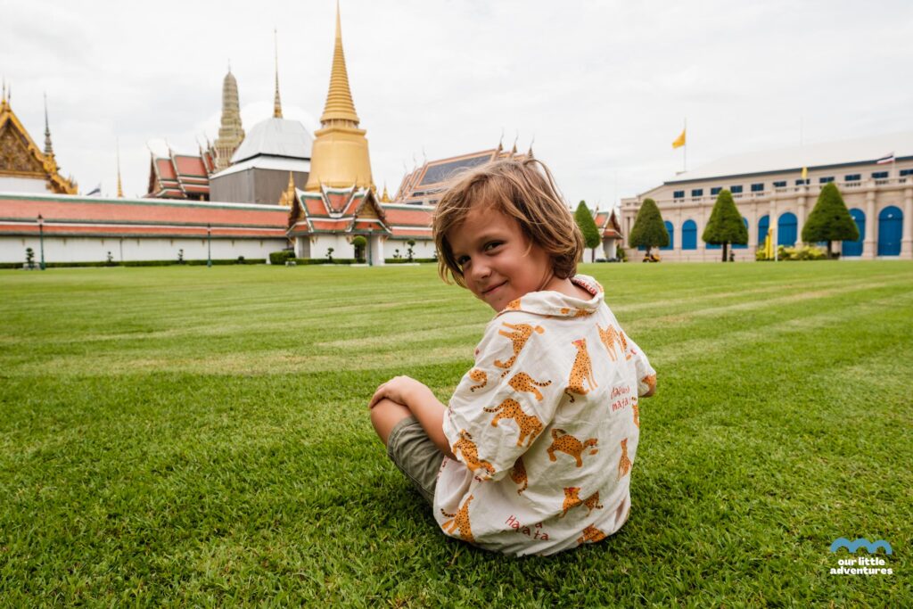 Chłopiec siedzi przed Kompleksem Pałacowym Grand Palace w Bangkoku; zdjęcie z tekstu: Które świątynie w Bangoku warto zobaczyć (z dziećmi lub bez)? na blogu Ourlittleadventures.pl