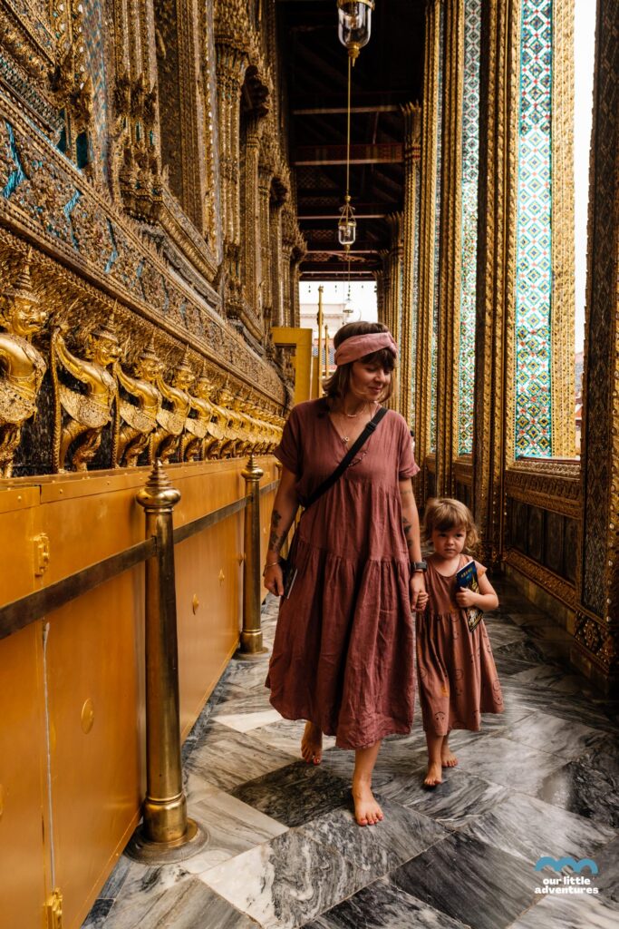 Kobieta z dziewczynką idą przy Wat Phra Kaew - Świątyni Szmaragdowego Buddy w Bangkoku; zdjęcie z tekstu: Które świątynie w Bangoku warto zobaczyć (z dziećmi lub bez)? na blogu Ourlittleadventures.pl