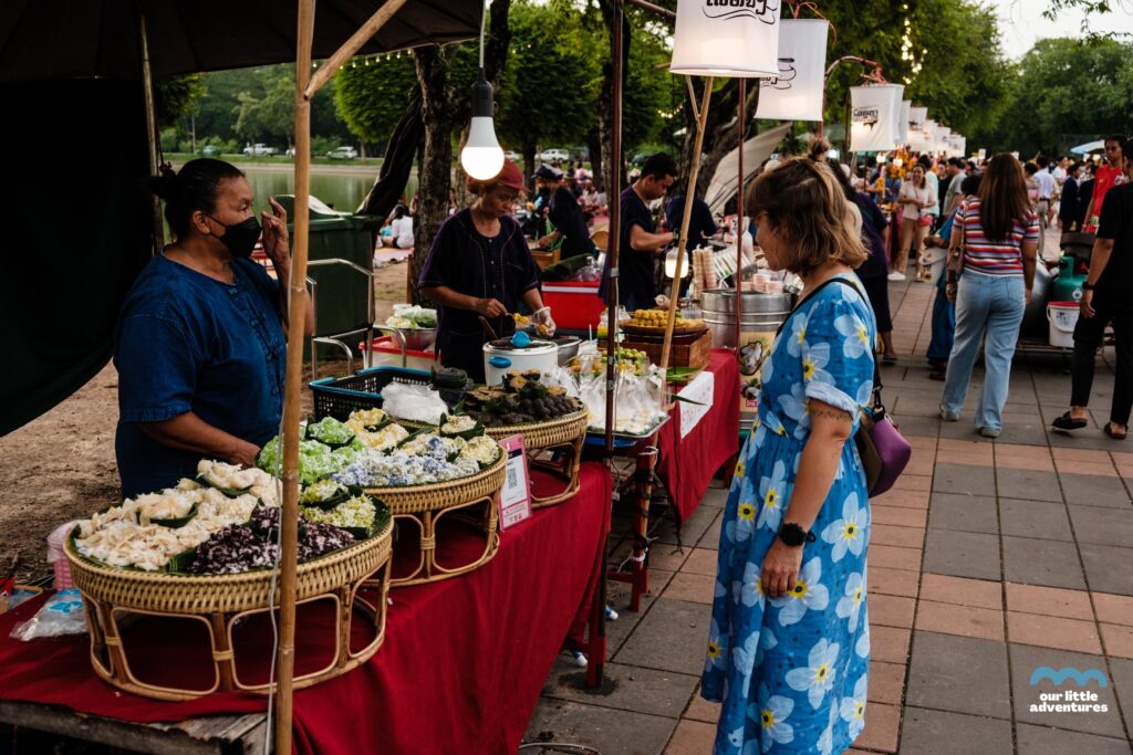 Nocny market w Parku Historycznym Sukhothai kobieta przegladajaca stoisko z tajskimi slodyczami.