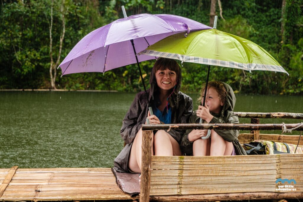Matka z córką na bambusowiej tratwie na jeziorze w królewskim parku Pang Oung podczas ulewy